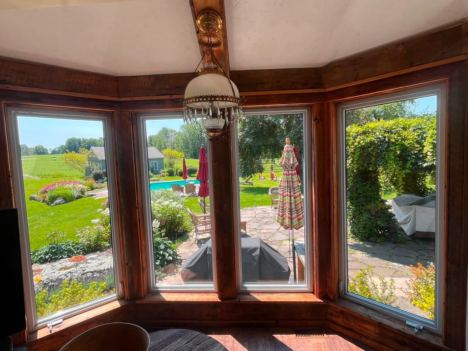 Caledon sunroom after full glass replacement — crystal-clear view of the garden and pool through four newly installed sealed glass units