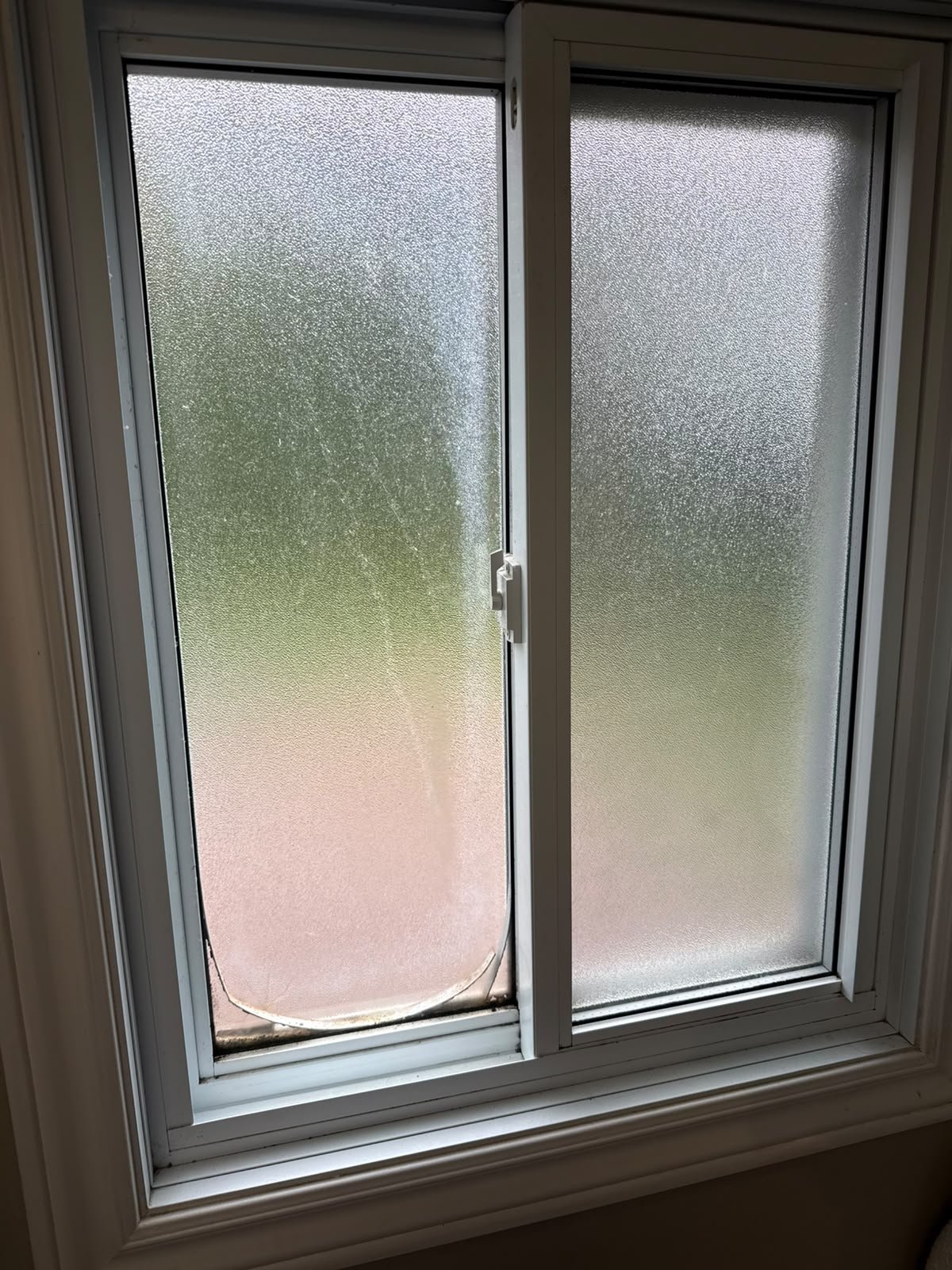 Damaged frosted glass sliding window with visible mark on bottom pane before replacement in Orangeville